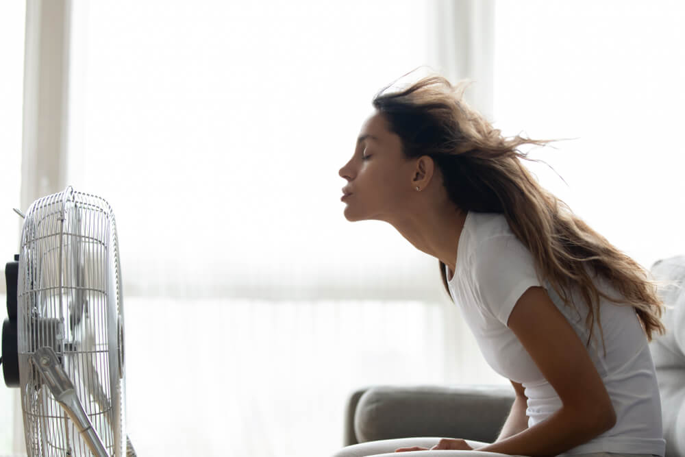 Electric fan blowing warm air in modern interior, showing limited effectiveness without portable air con in enclosed spaces
