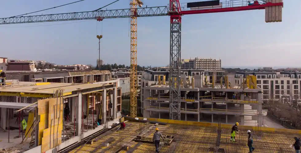 Aerial view of large urban construction site with cranes, concrete structures and groundwork operations requiring construction dust control measures